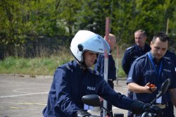 alt=&quot;Policjant w hełmie na motocyklu przed startem w konkurencji sprawnościowej.&quot;